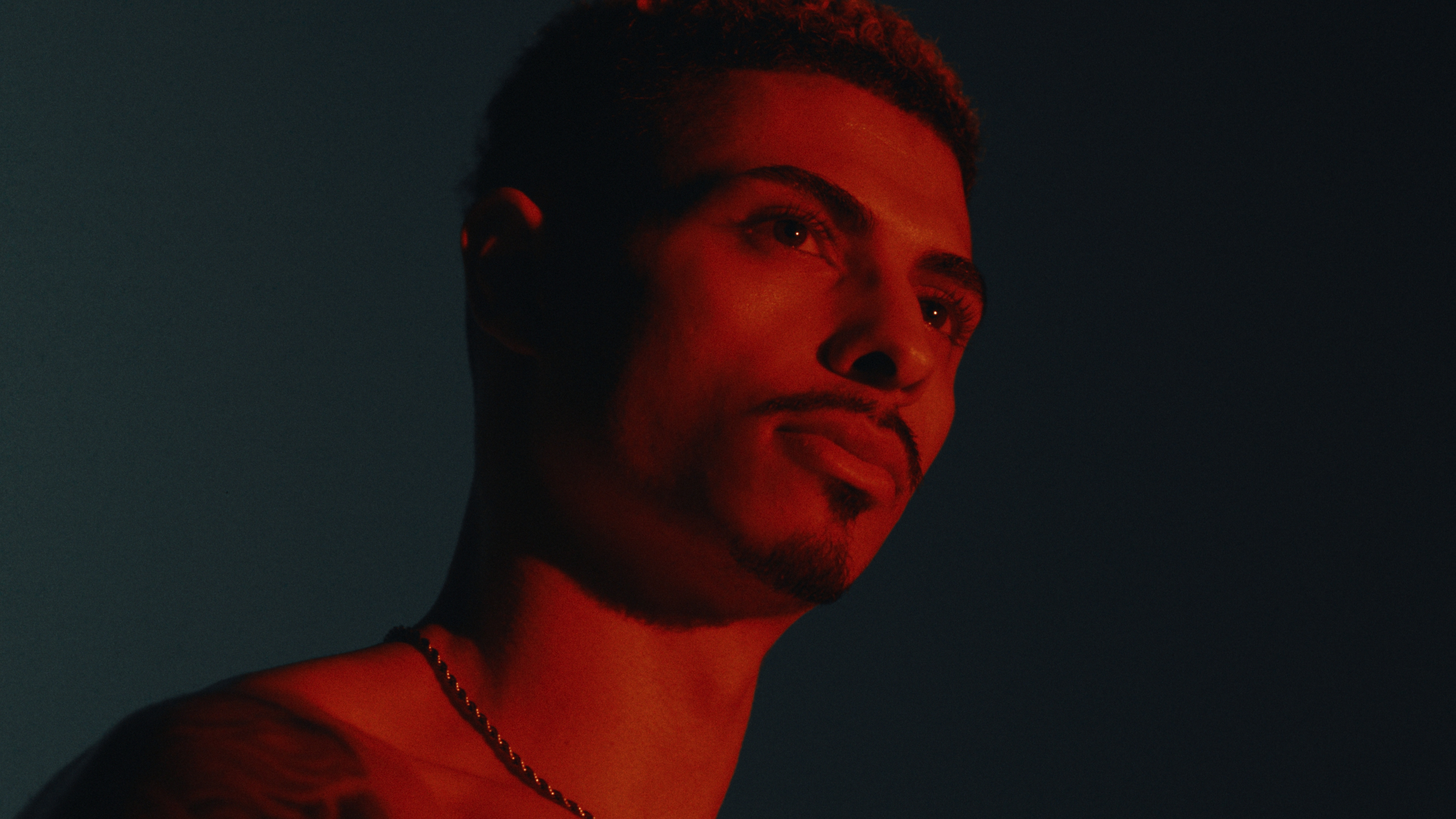 Portrait of an athlete's face lit in deep red against a dark blue backdrop