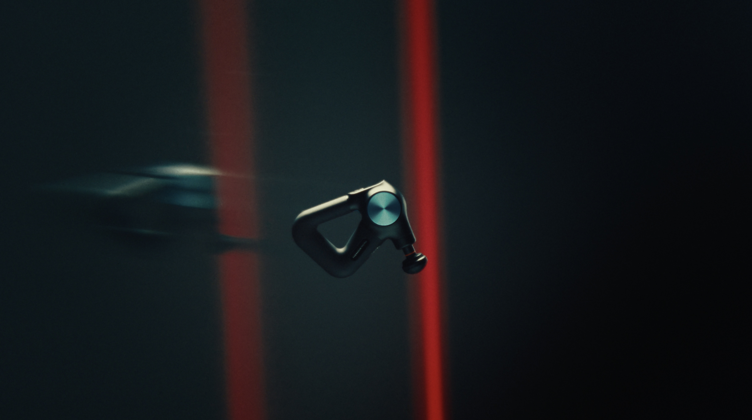 Theragun Pro Plus suspended midair against streaks of red light