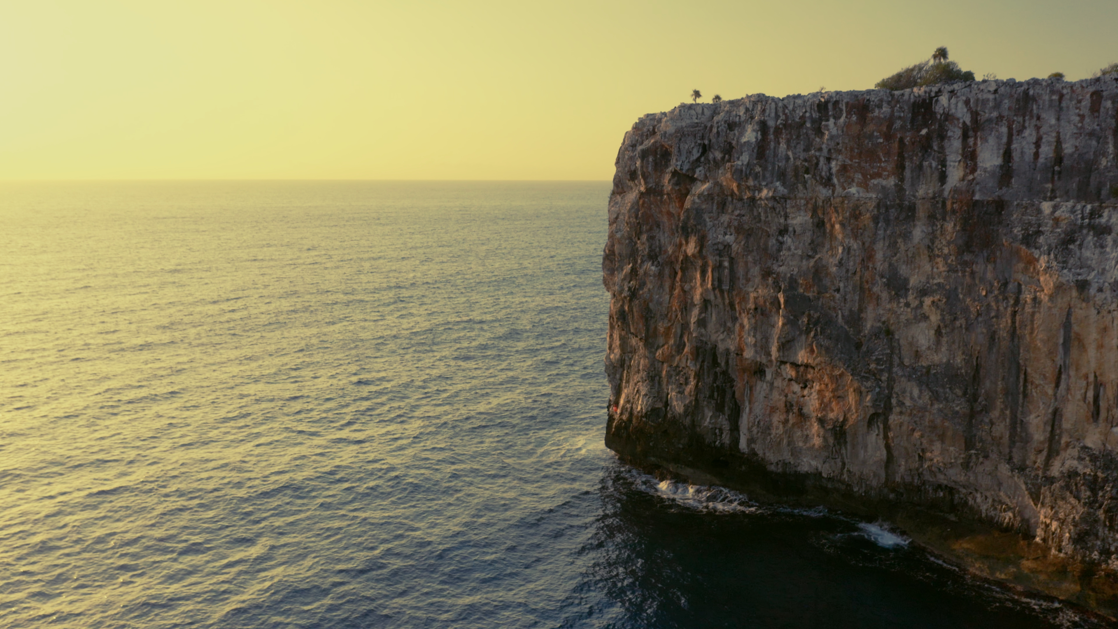 Golden morning light on the sea cliffs of Cayman Brac above calm water
