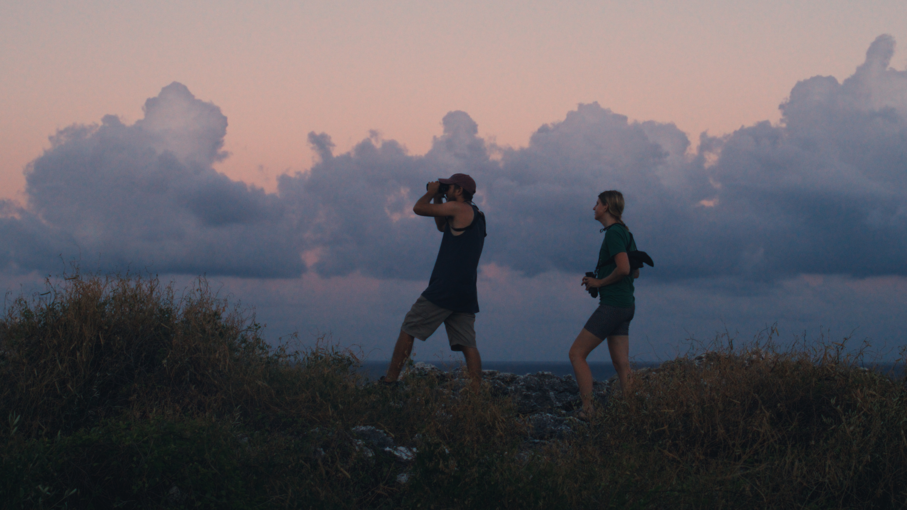 Two people walking a coastal ridge at dusk