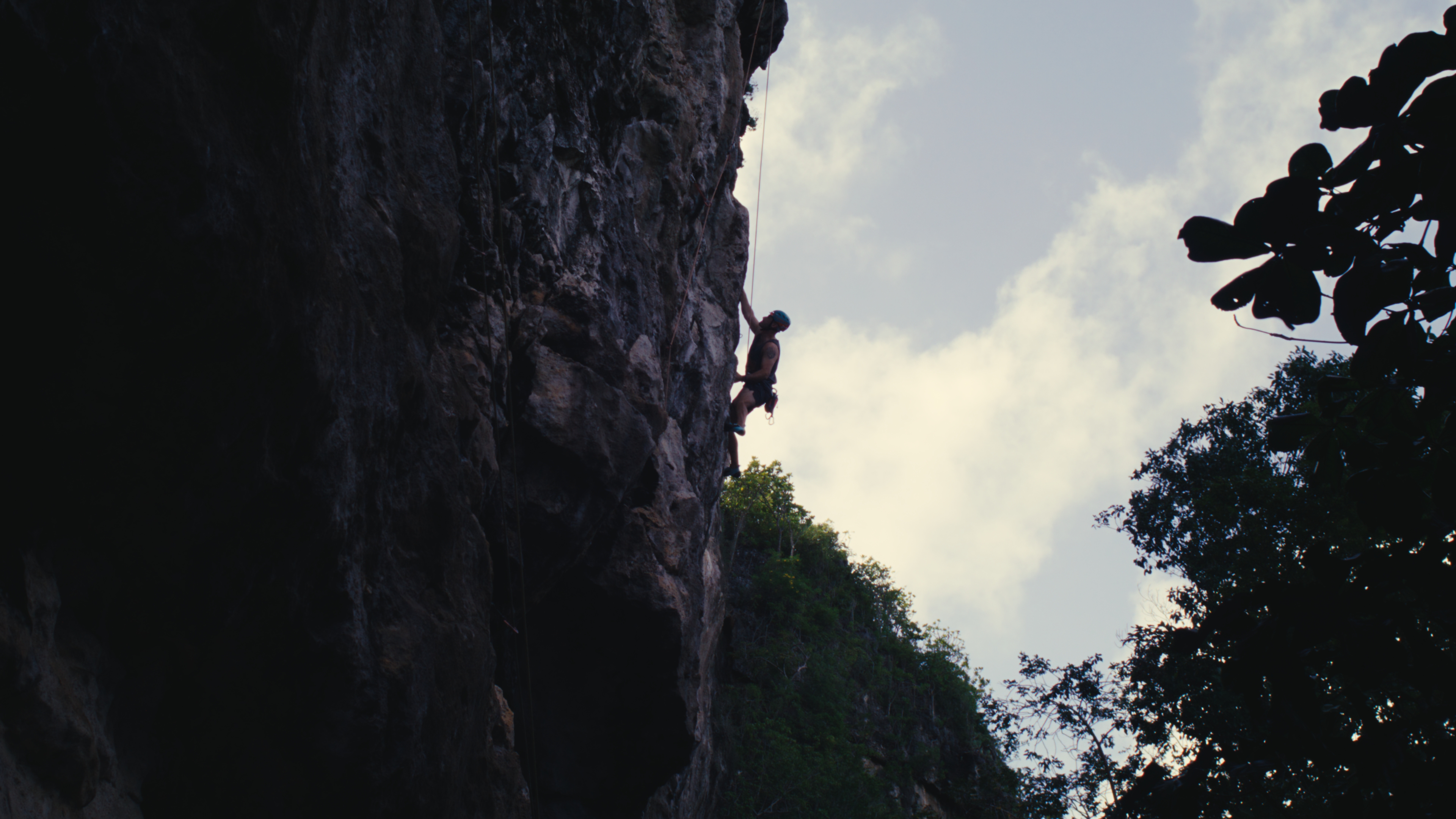 Climber scaling a shaded limestone cliff face