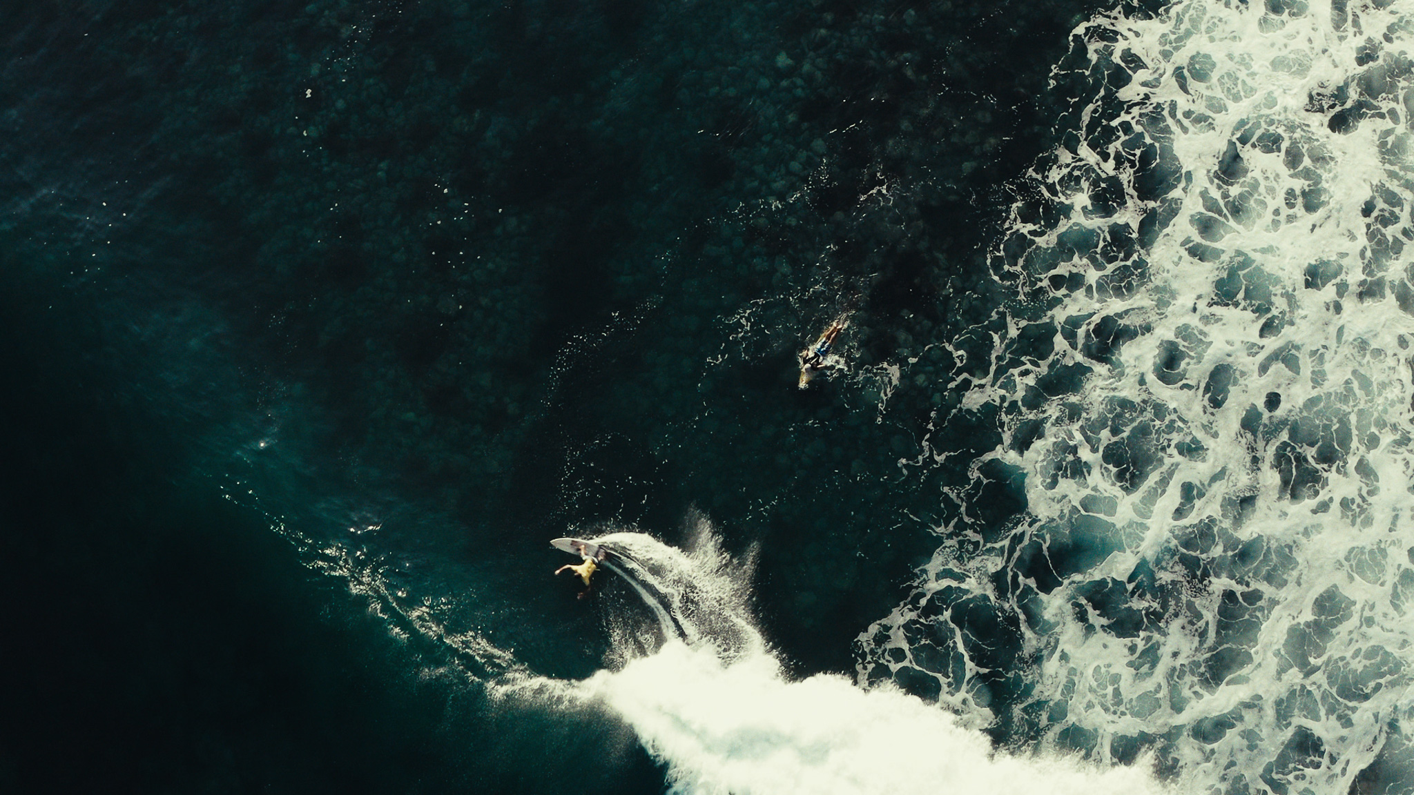 Overhead view of a churning wave as a surfer duck-dives below