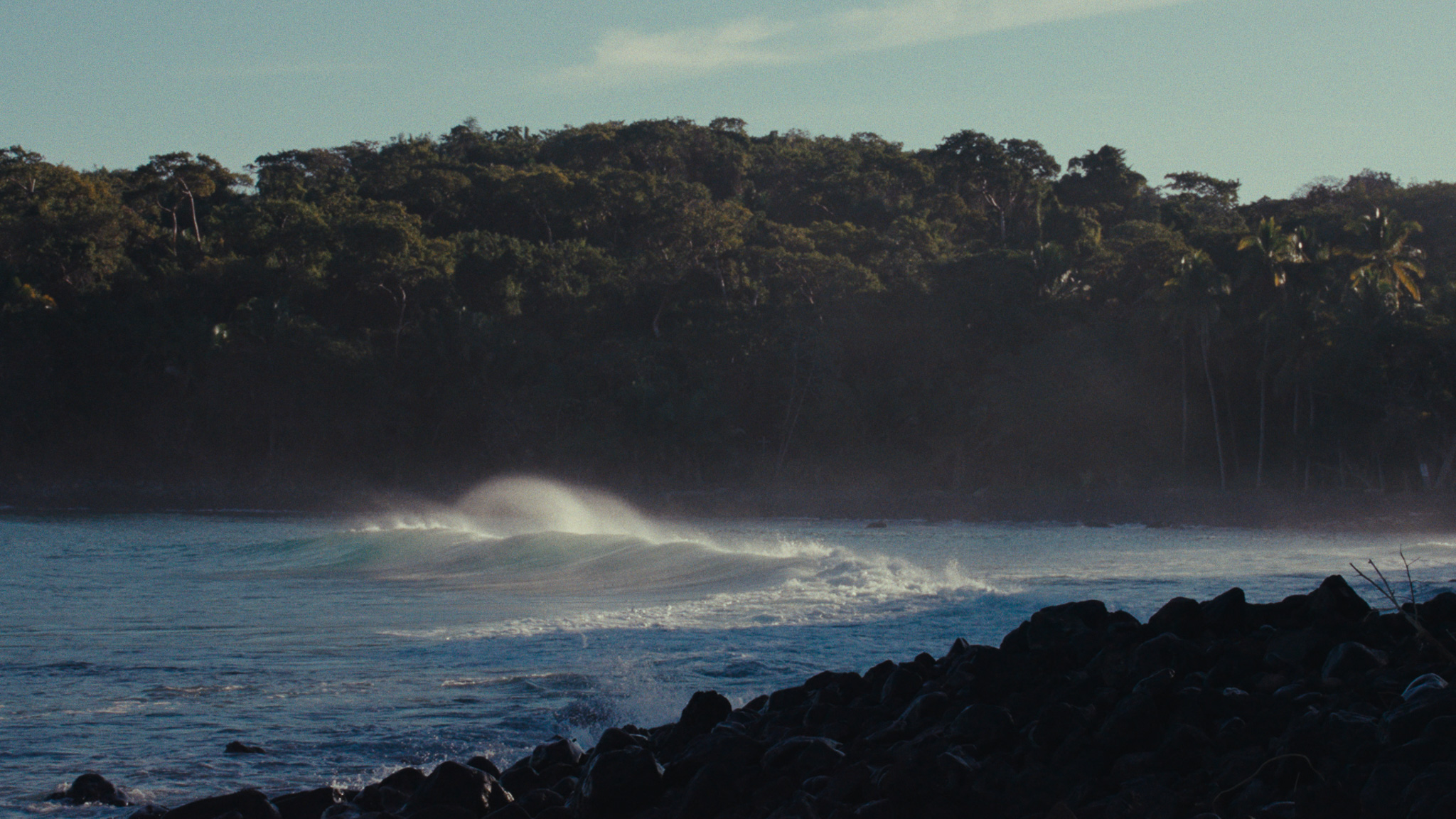 Waves breaking on a rocky shore below the jungle