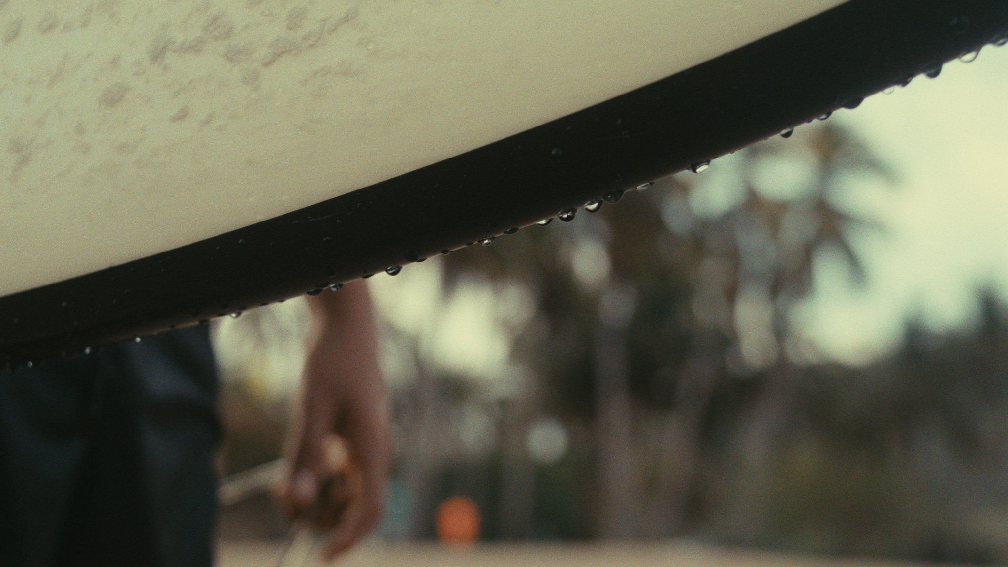 Surfboard rail dripping with water against a blurred beach town