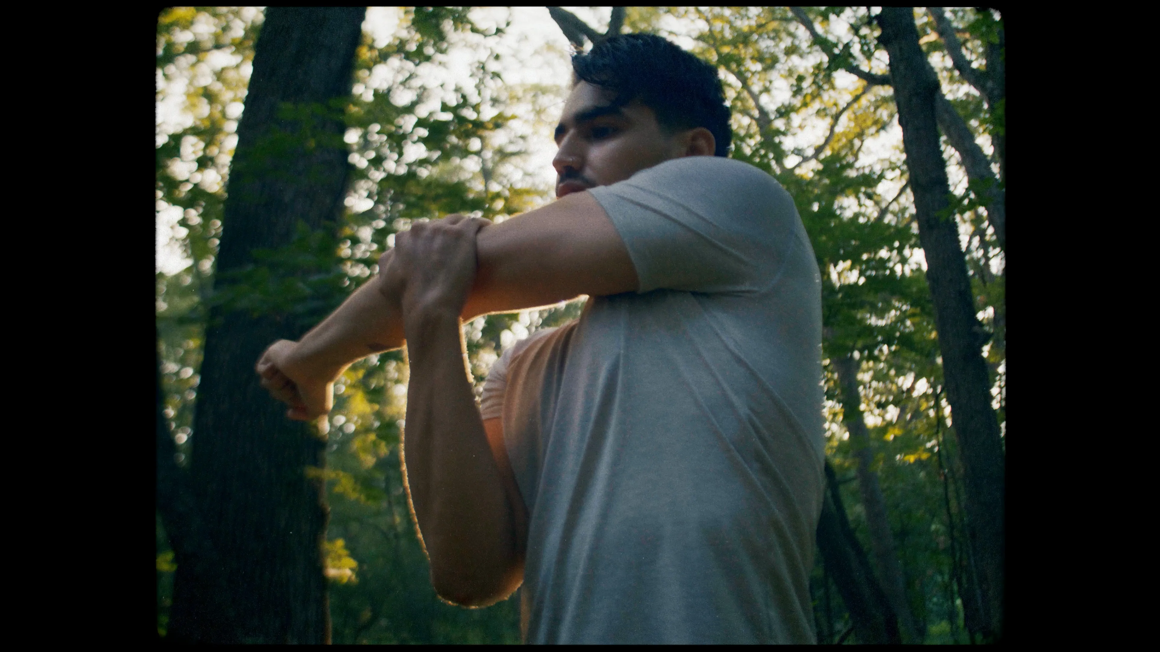 Runner stretching an arm among the trees before a run