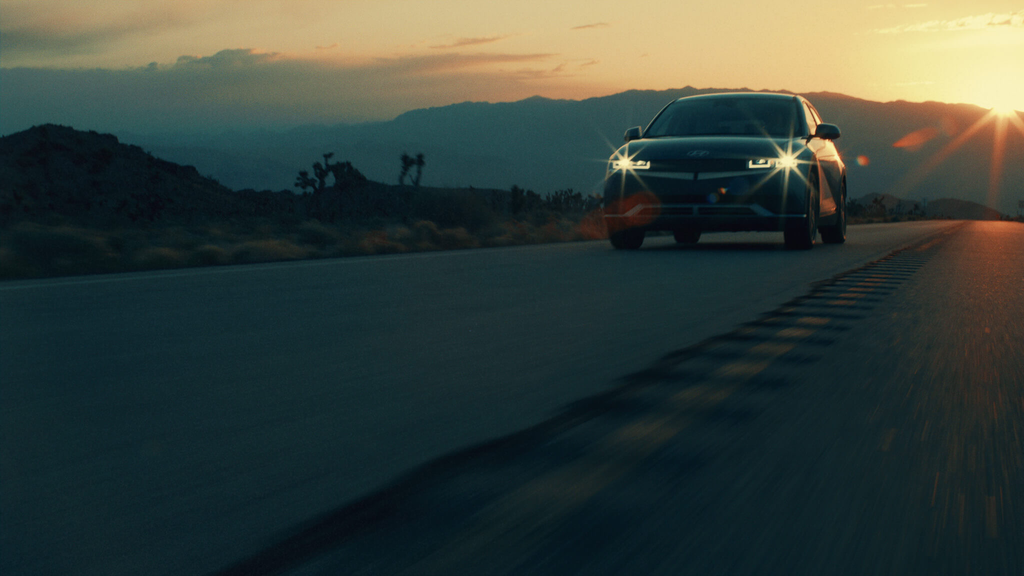 Hyundai IONIQ 5 driving a desert road into the sunset