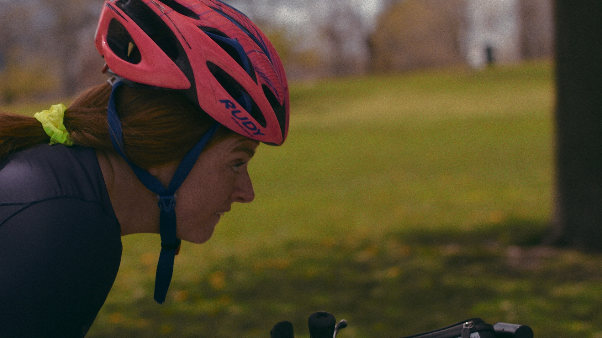 Mary Kate in a pink helmet riding a handcycle in profile
