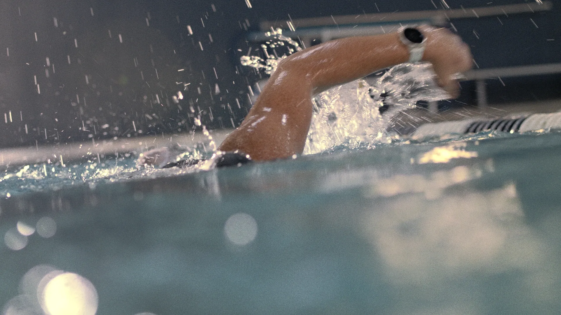 Freestyle swimmer mid-splash wearing a sports watch