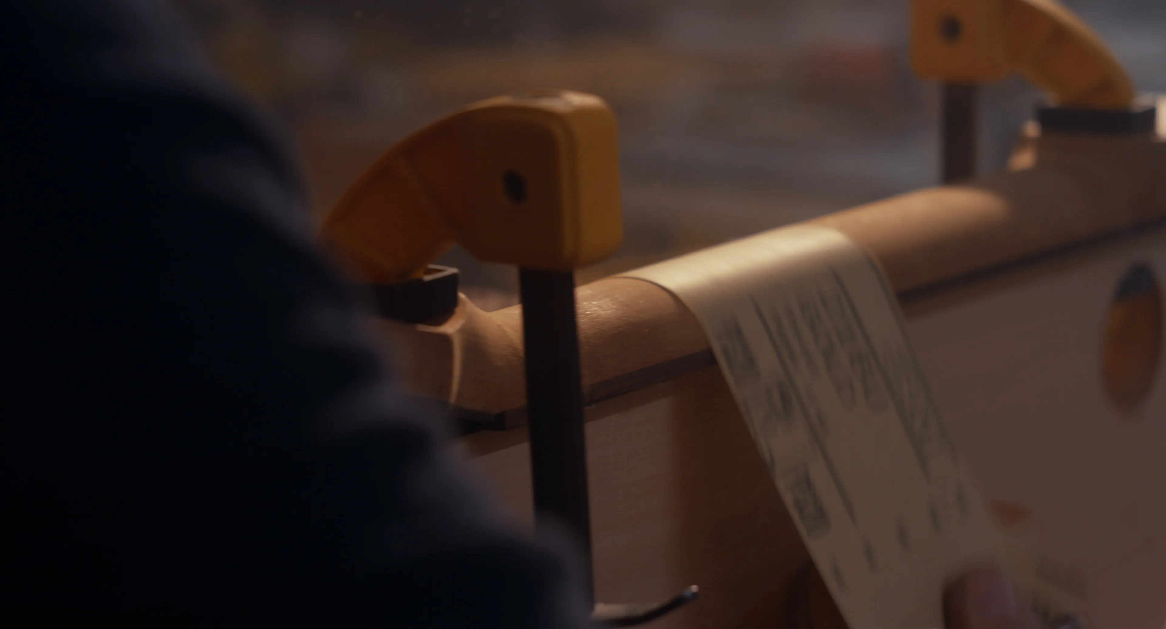 Hands sanding a clamped guitar neck