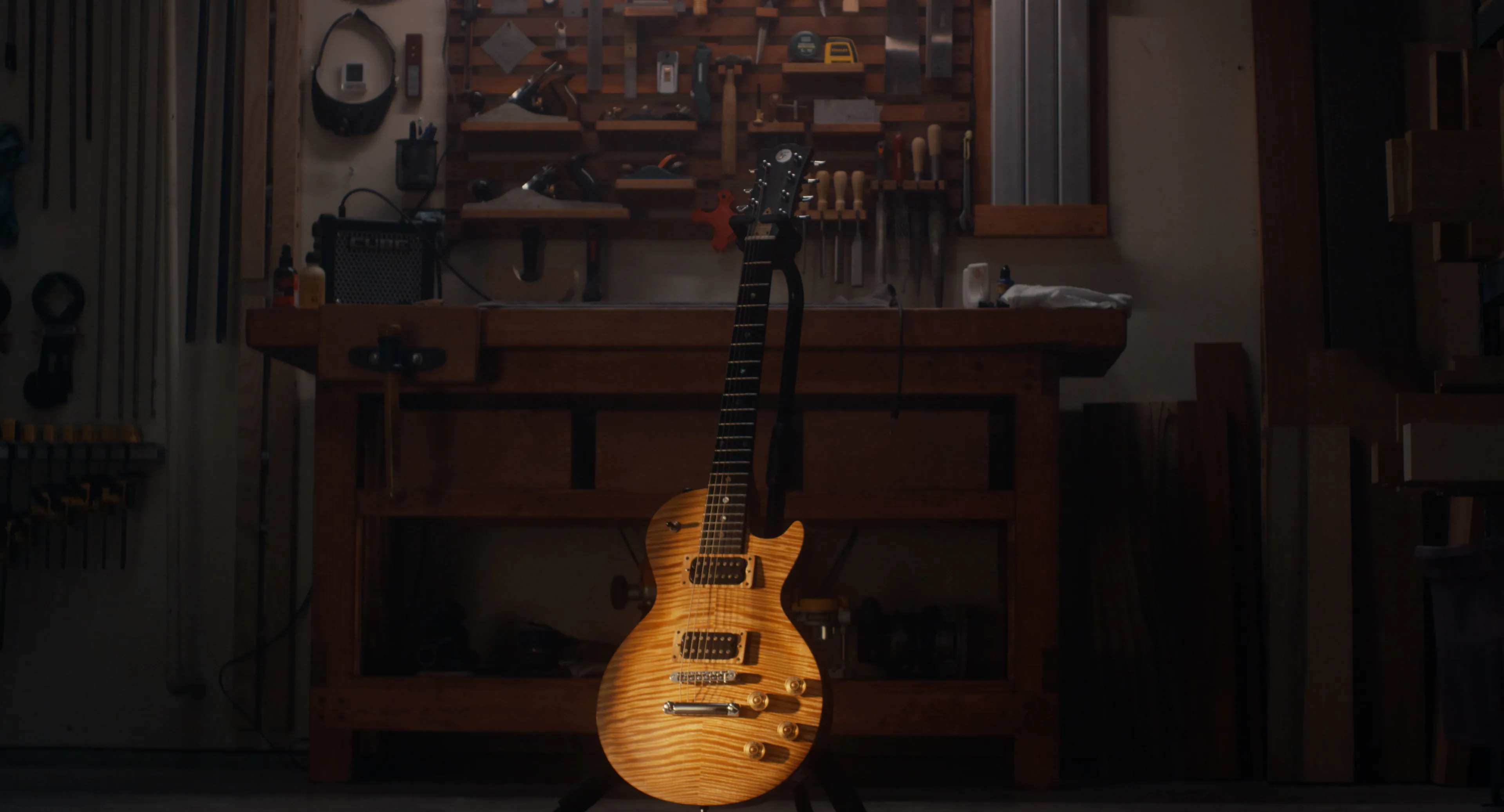 Finished electric guitar standing in the workshop with tools on the wall behind