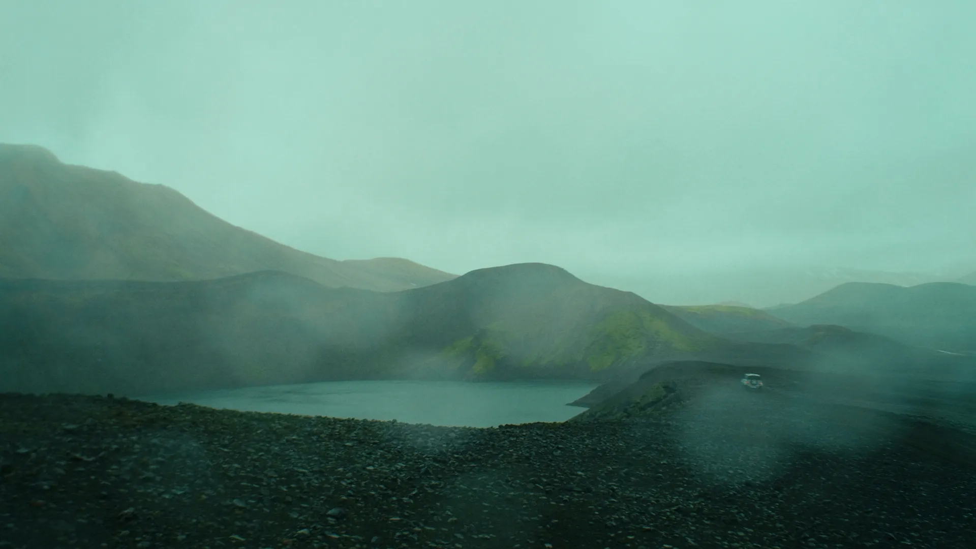 Misty highland lake between mountains with the Defender in the distance