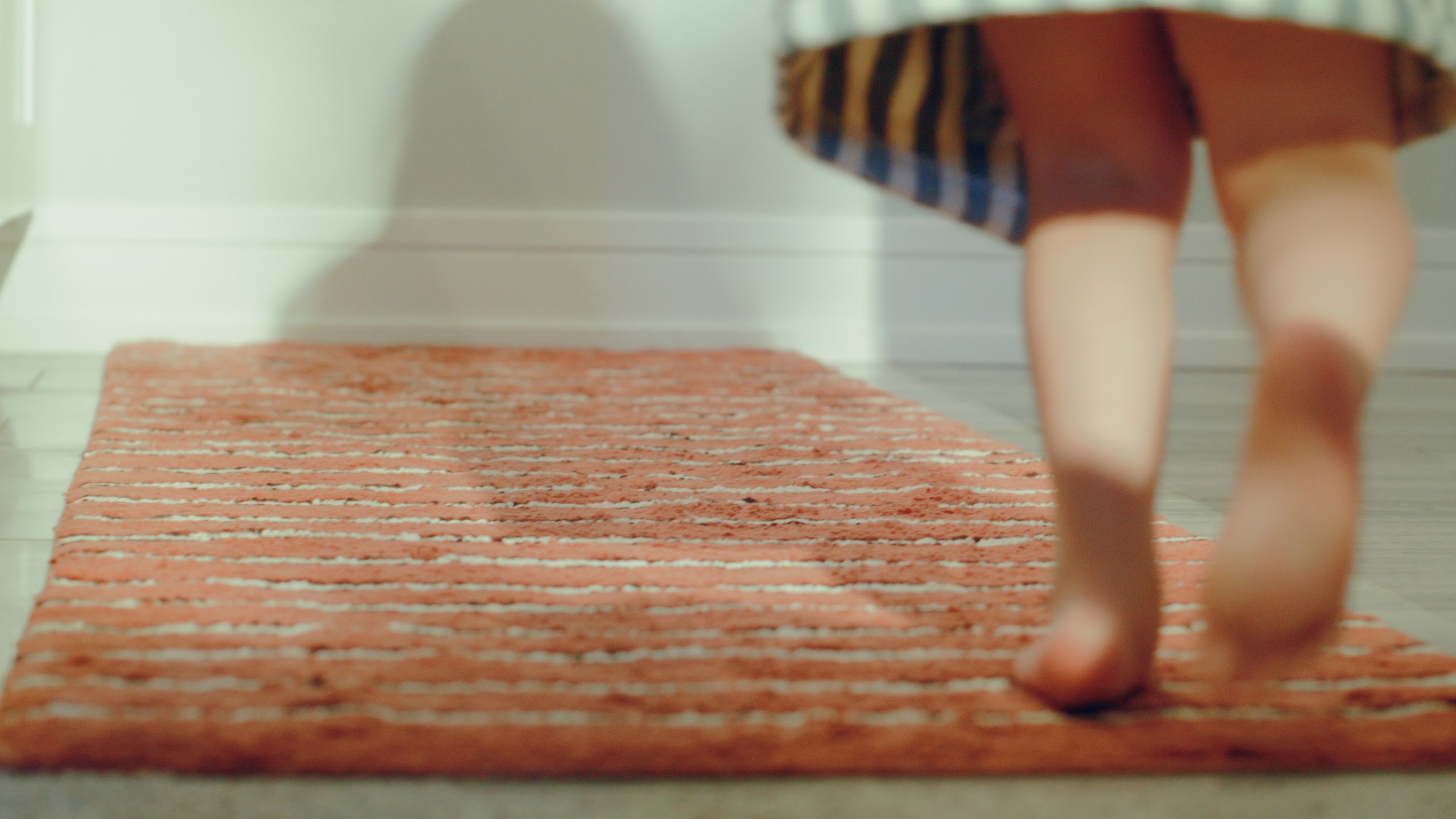 Bare feet crossing a woven rug on a school morning