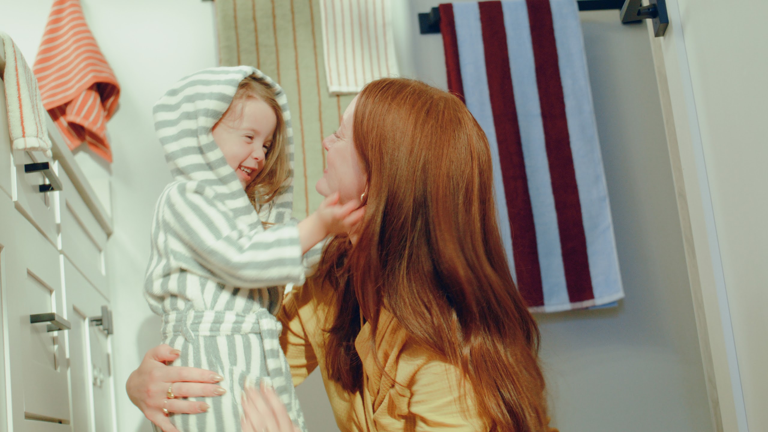 Girl in a striped robe with her mother in the hallway