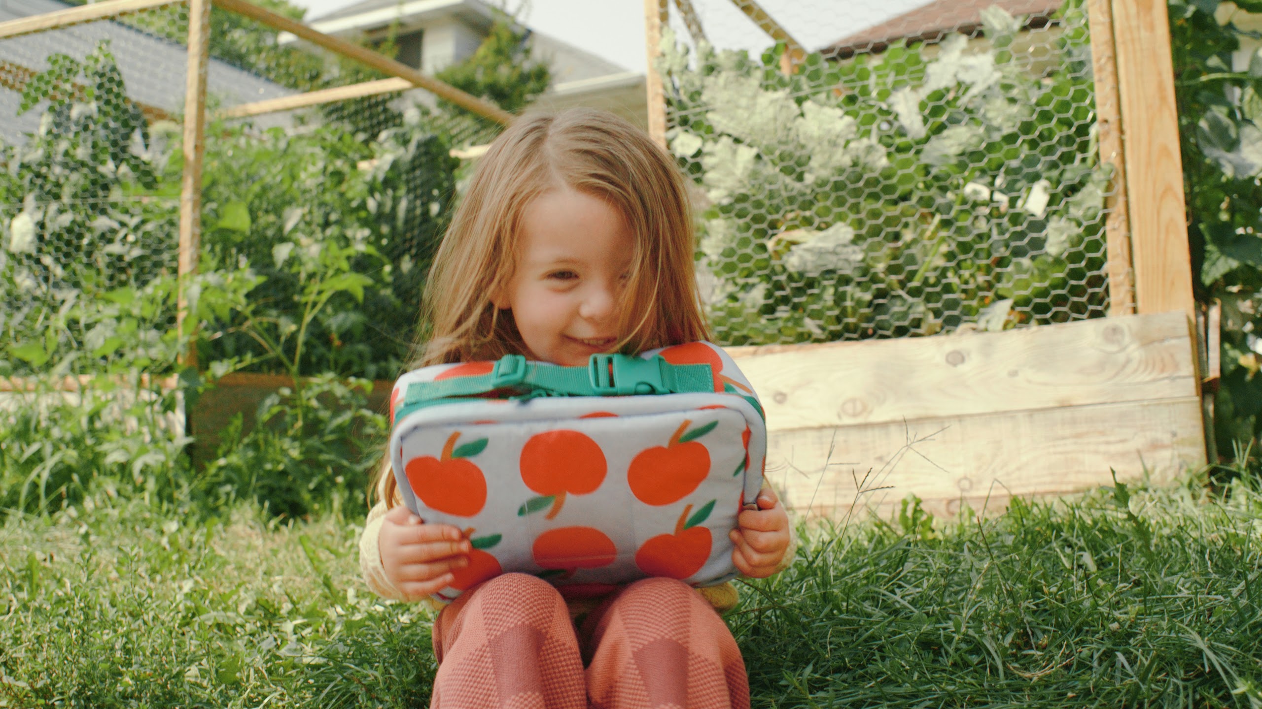 Girl holding the apple print bag in the grass