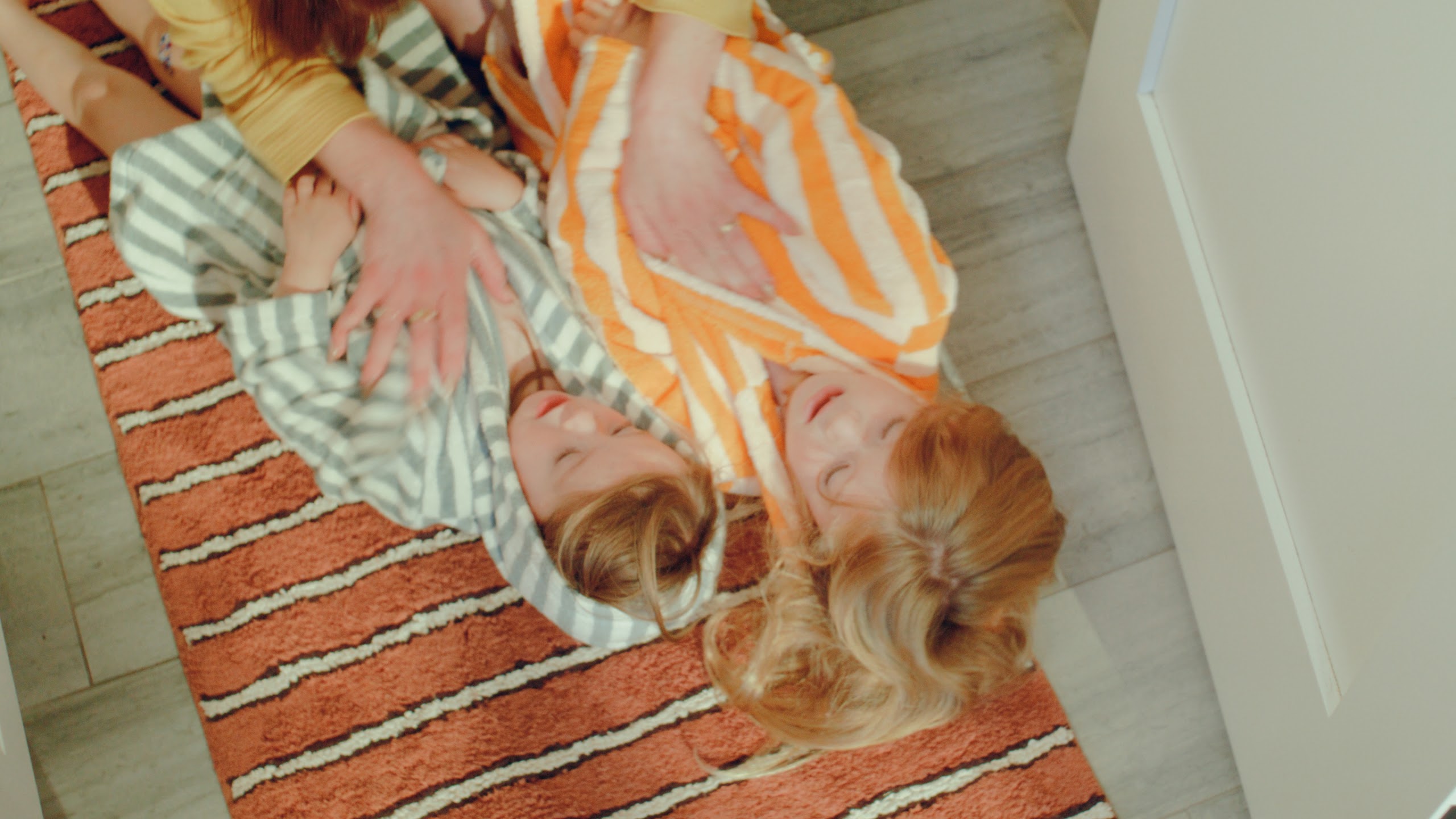 Sisters tumbling together on a striped rug