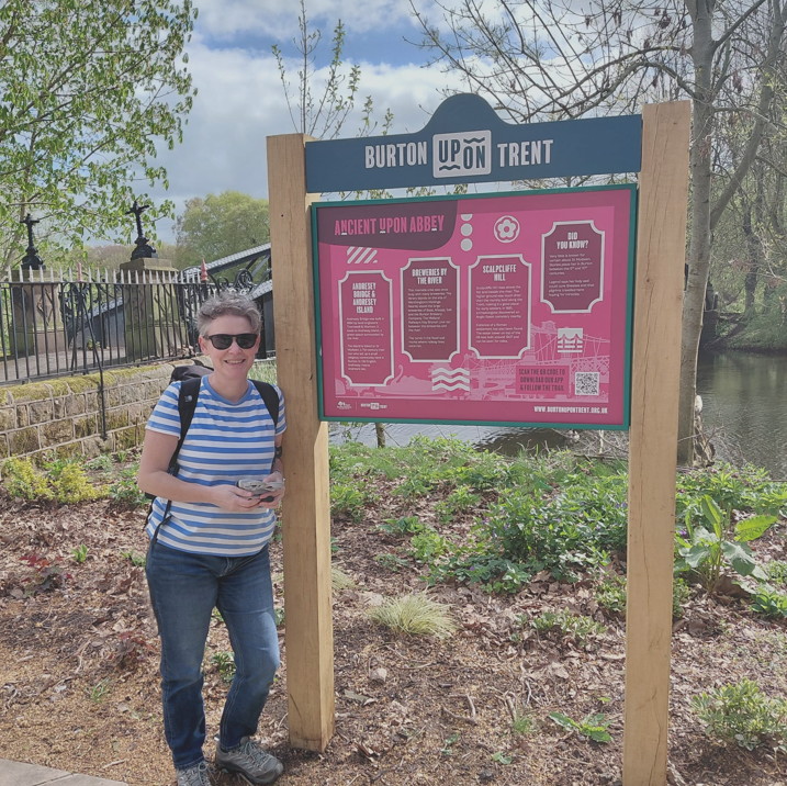 Helen Young standing next to the interpretation boards she wrote in Burton on Trent