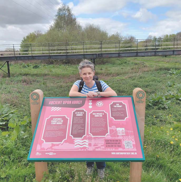 Helen Young standing next to the interpretation boards she wrote in Burton on Trent