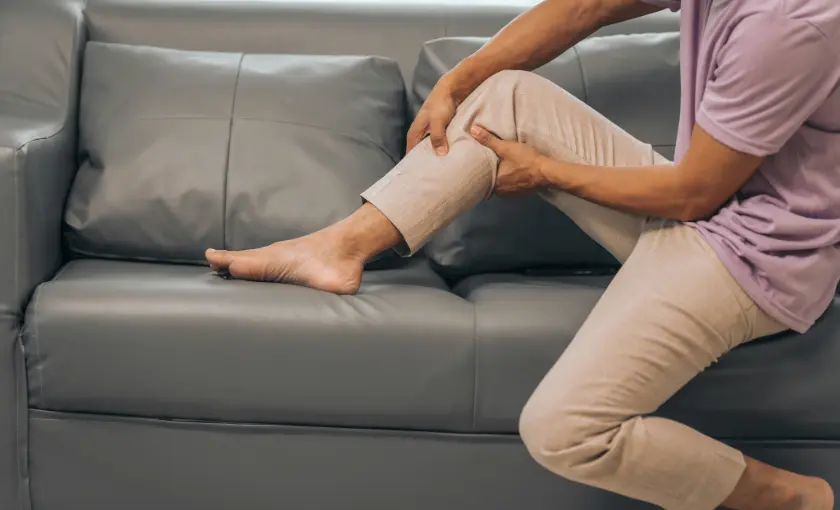 Person massaging calf to relieve leg cramps caused by medication side effects.