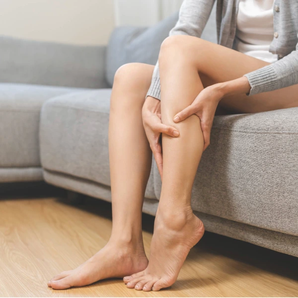 Patient holding their lower leg due to heaviness and discomfort caused by venous insufficiency.