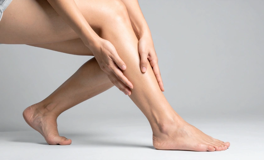 Person rubbing a tired, heavy lower leg with mild swelling.