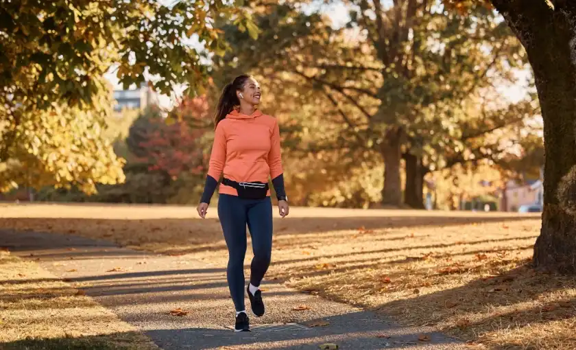 Woman in light exercise clothing walking on a park path during DVT recovery.