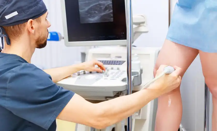 An ultrasound technician examining a patient's leg for venous disease