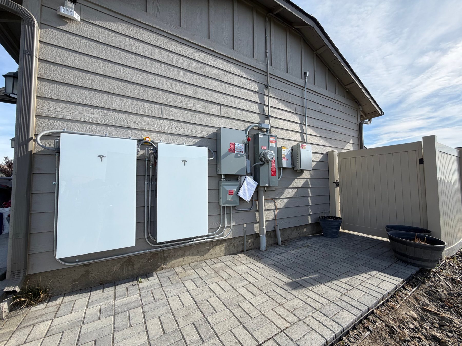 Two Tesla Powerwall batteries installed on the outside wall of a home