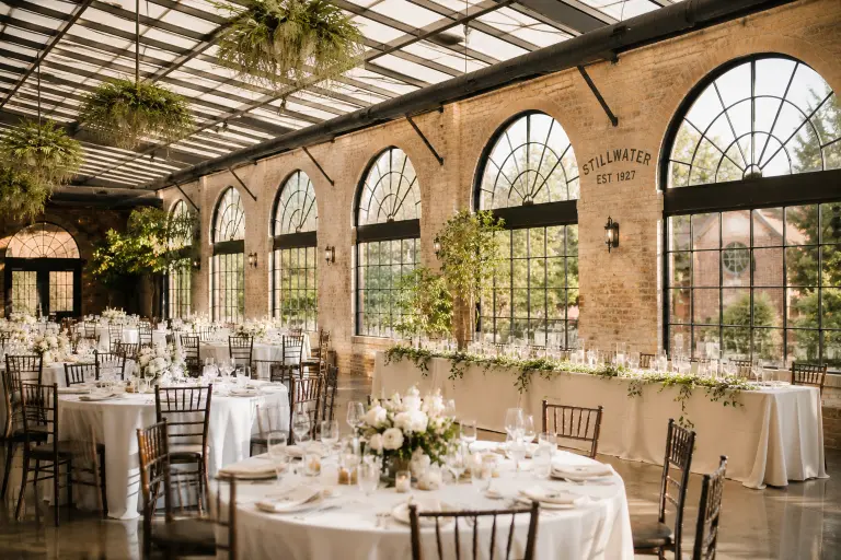 Bright, airy wedding reception in The Solarium at Stillwater in McMinnville, with natural light streaming through lunette windows, creating an elegant and romantic atmosphere.