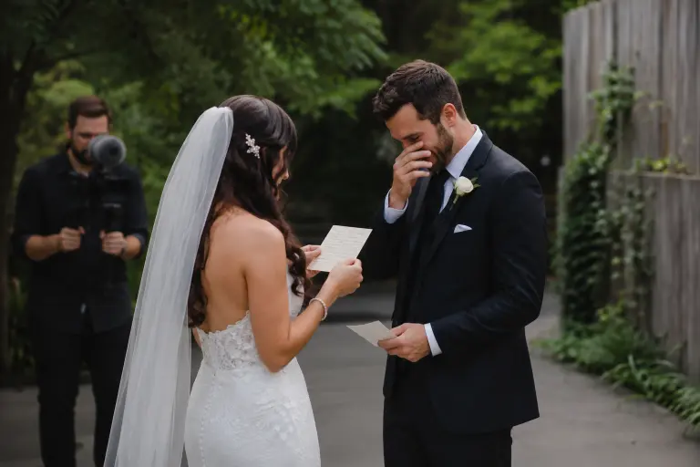Couple reading handwritten private vows to each other during wedding first look with videographer capturing audio