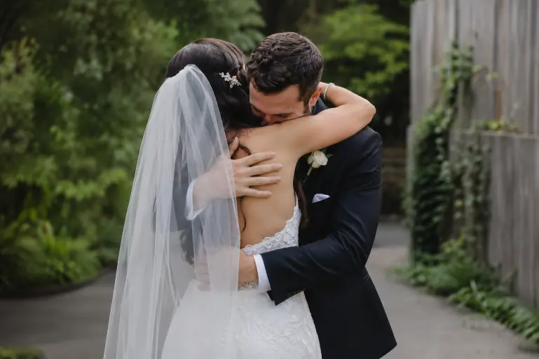Bride and groom embracing during an emotional wedding first look with soft natural light and intimate outdoor atmosphere