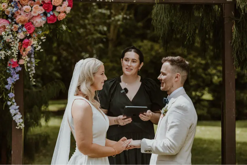 Bride and groom exchanging vows during an outdoor wedding ceremony while the officiant speaks, highlighting the importance of clear wedding videography audio for capturing meaningful moments.