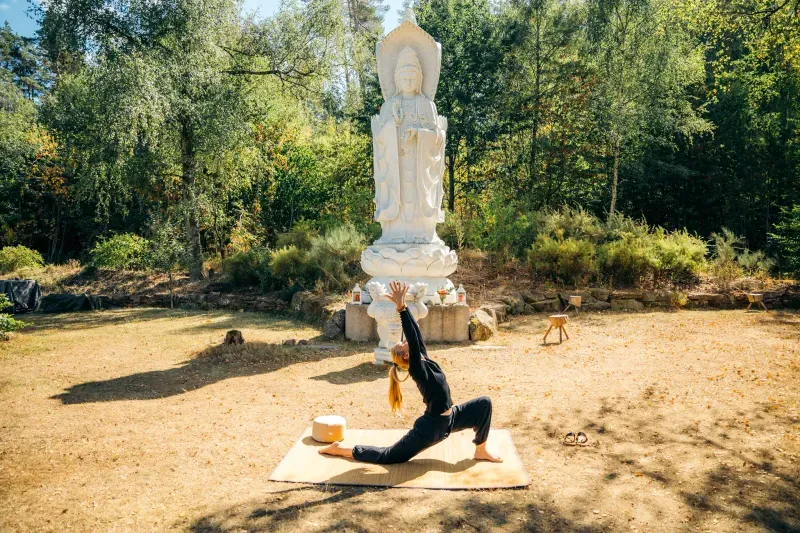 Eine Frau macht Yoga vor einer Buddhistischen Statur