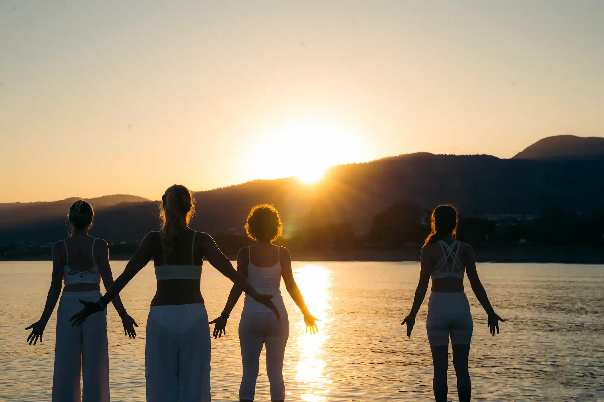 Vier Frauen welche zum Sonnenaufgang am Meer auf Zypern Yoga praktizieren