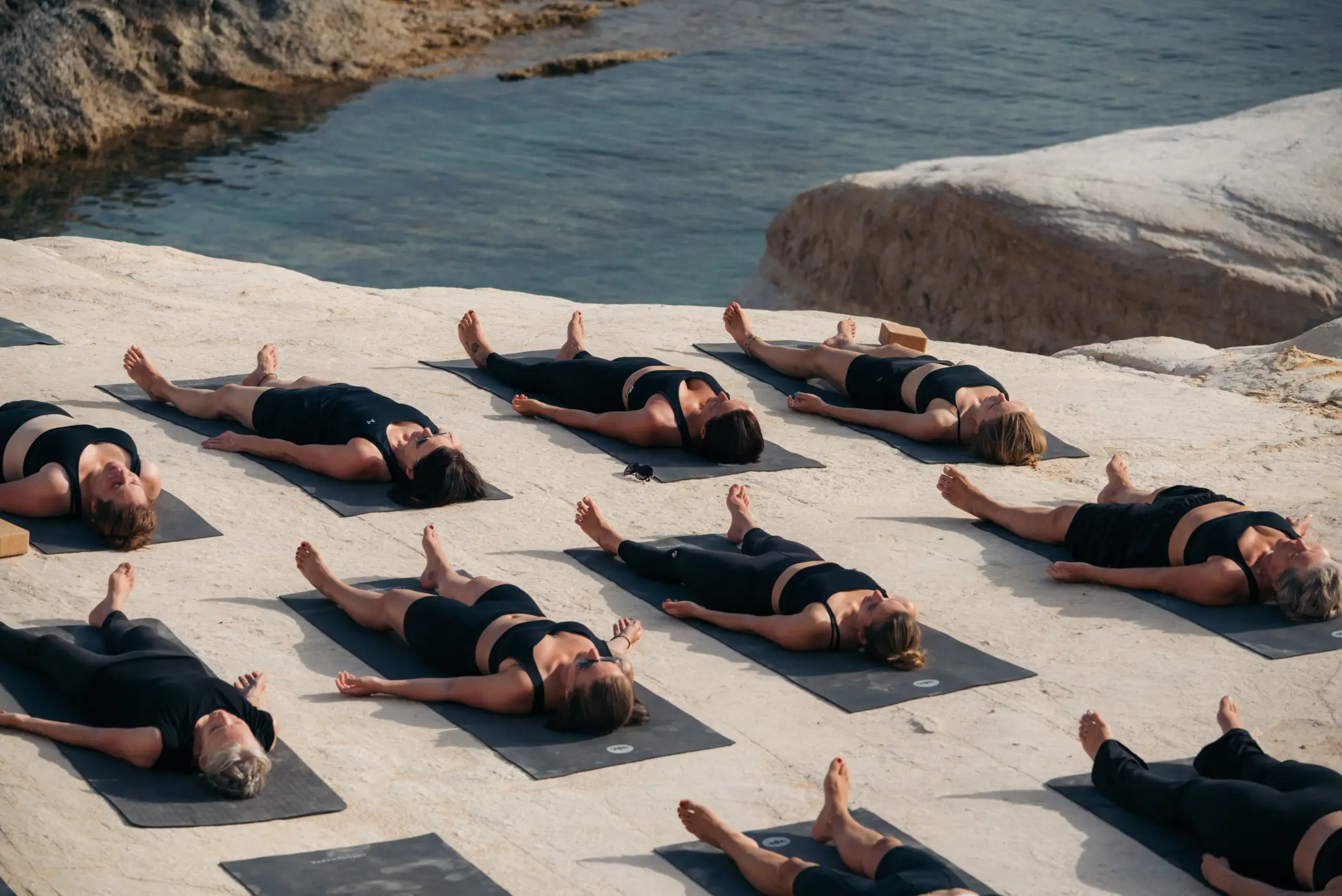 Teilnehmerinnen der Hybrid-Ausbildung strecken die Arme bei Abendlicht auf der Yoga Shala