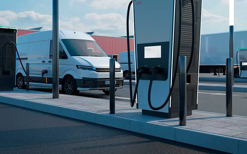 Electric van charging at a modern EV charging station in an industrial area.