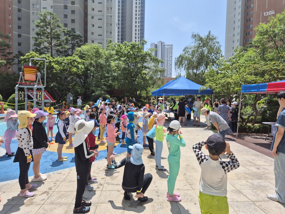 여름방학 물놀이장 개장행사에 참여한 송도더샵퍼스트파크13단지 입주민들이 물놀이 사전 준비운동을 하고 있다. [사진=관리사무소]