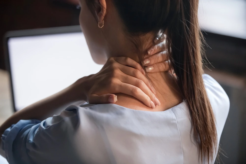 Frau fasst sich schmerzerfüllt an Nacken und Schultern – Symbolbild für Cannabis bei Fibromyalgie