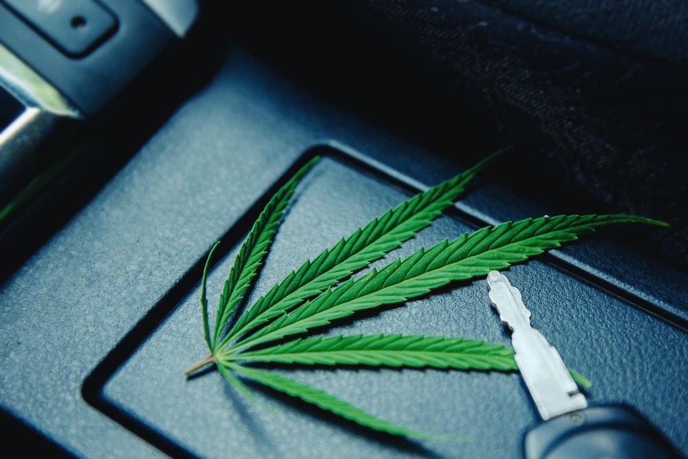 Cannabisblatt und Autoschlüssel im Fahrzeug – Symbolbild für Cannabis Grenzwert im Straßenverkehr