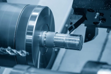 Close-up of a metalwork lathe machine cutting a cylindrical metal piece.