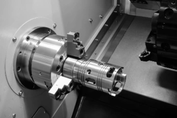Close-up of a metal workpiece mounted in a CNC lathe machine, showing precision machining details.