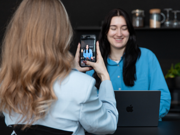 Ein Blick hinter die Kulissen der UGC: Man sieht eine Frau von hinten, wie sie eine Creatorin mit dem Smartphone filmt für Social-Media-Content.