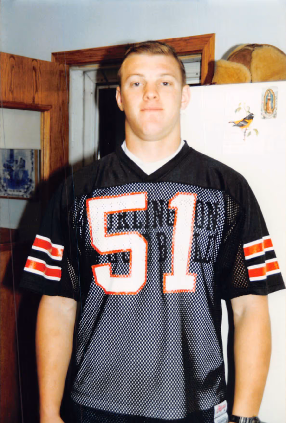 Young Paul Bondar wearing a black sports jersey with the number 51 standing indoors in front of a refrigerator.