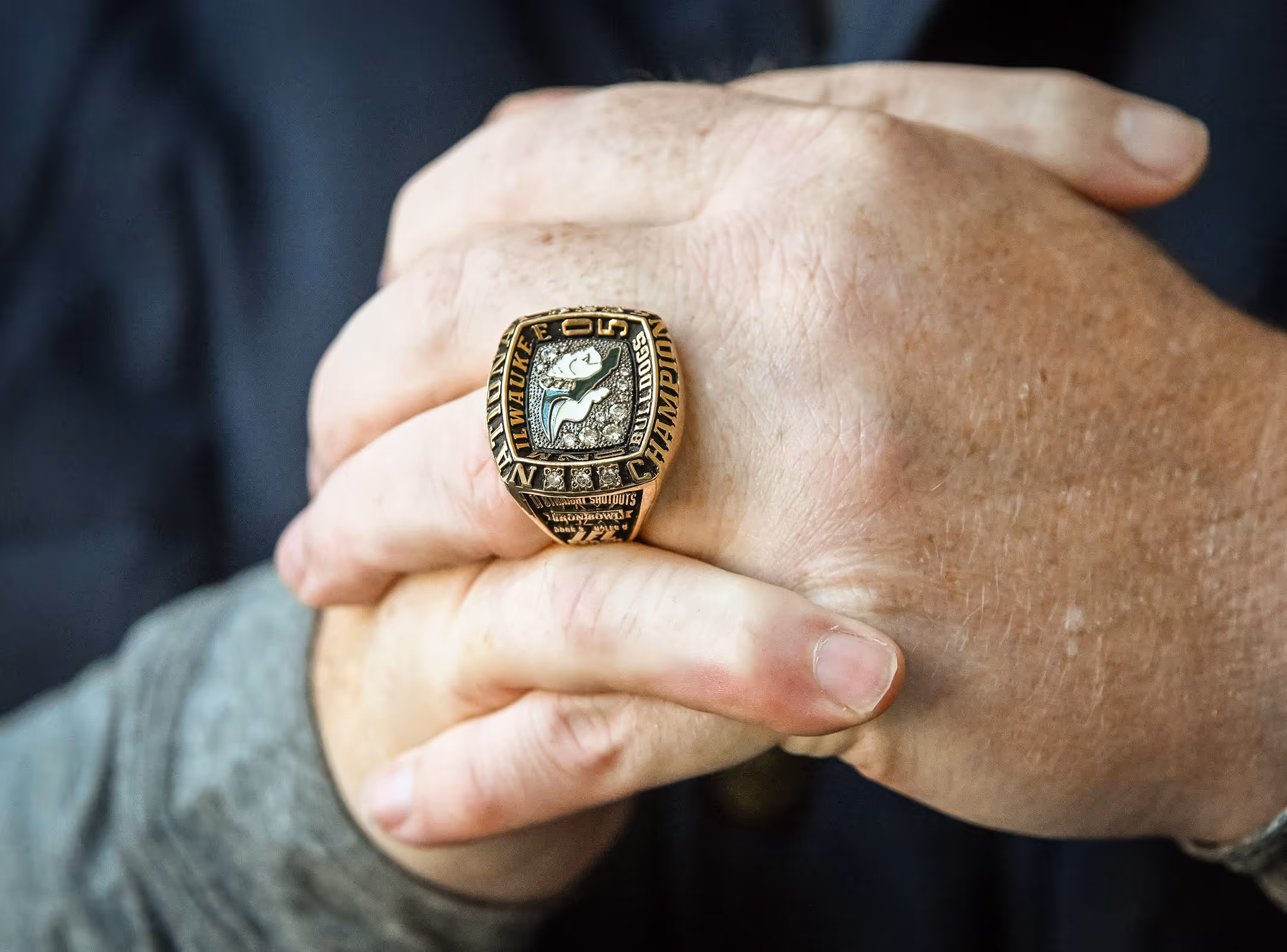 Close-up of hands clasped together with a large Milwaukee Bucks championship ring on one finger.
