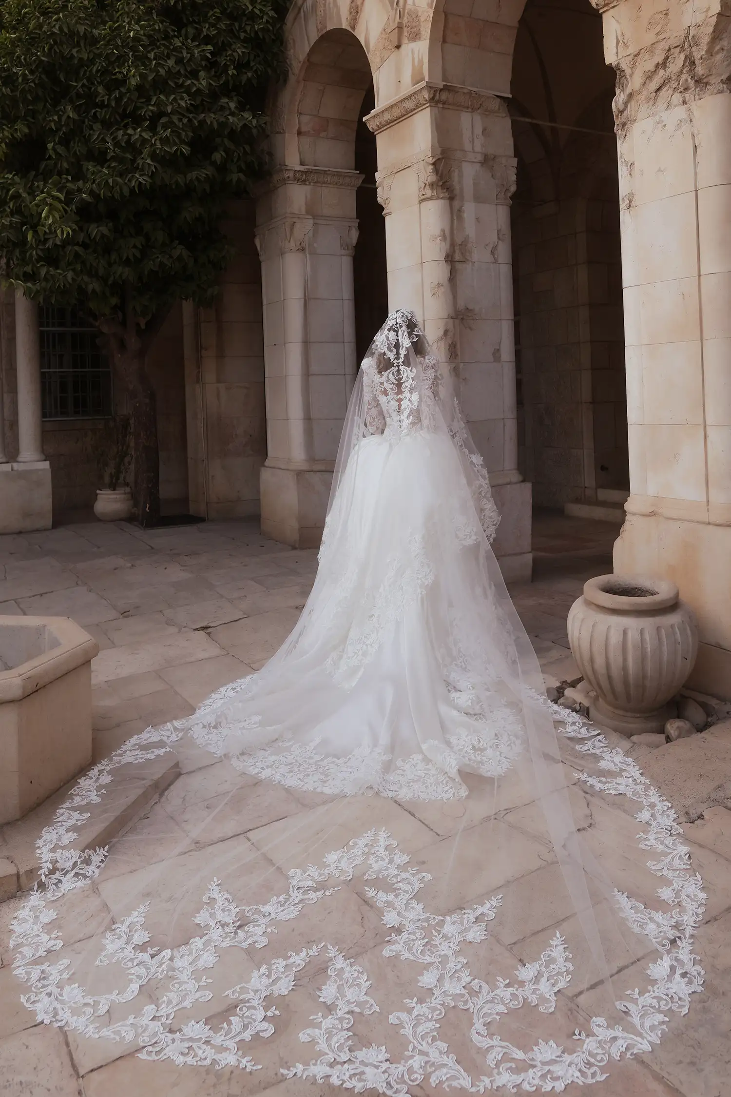 Beaded, dimensional flower embroidered boroque lace and silk organza ballgown, with tiered cutout skirt, high collar, and long puff sleeves. Shown with cathedral-length mantilla veil with beaded dimensional floral appliqué. 
