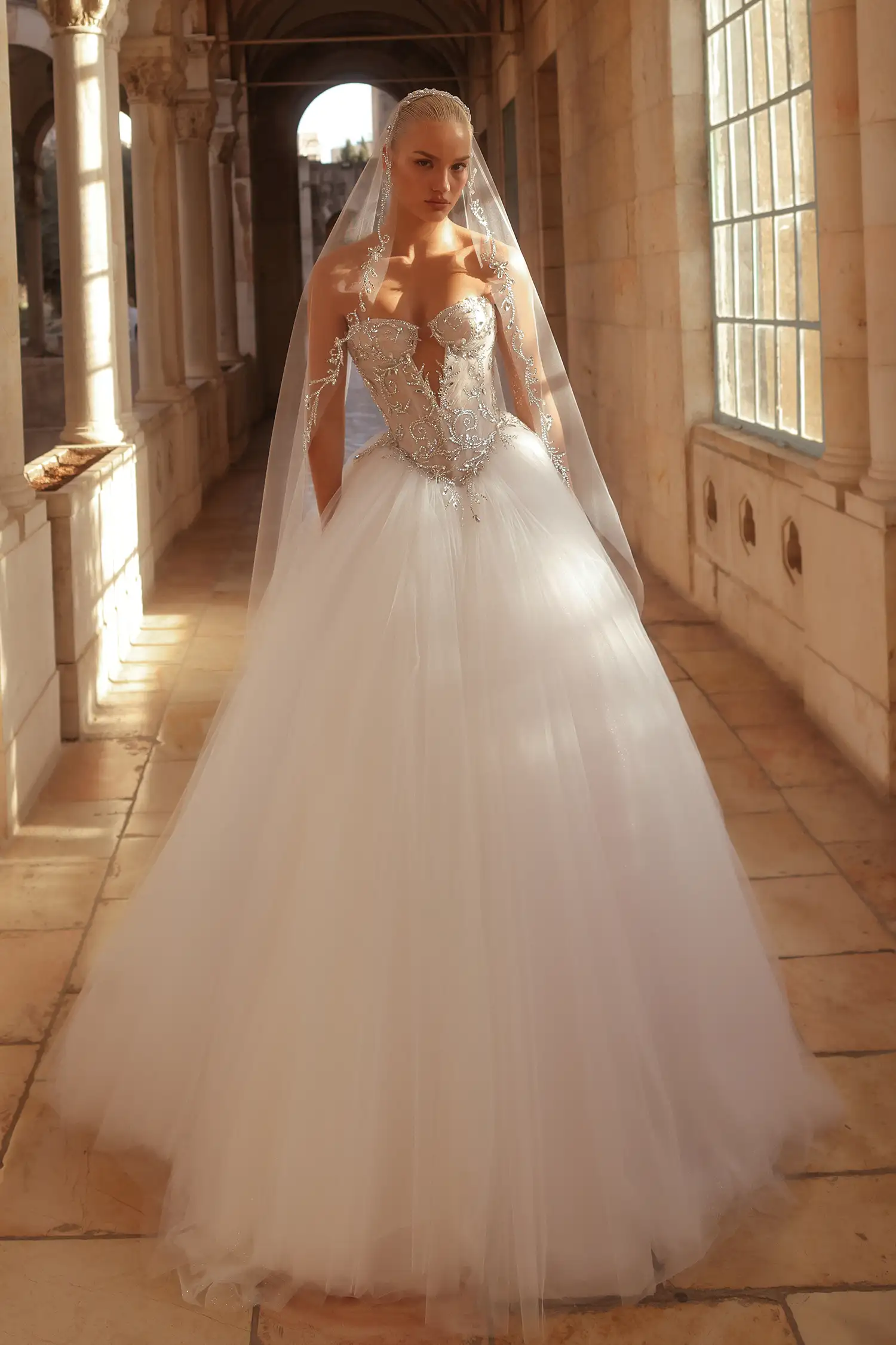 Strapless, sweetheart neckline ballgown with tulle plissé bodice fully embellished in mirror crystals and full tulle skirt with glitter underlay. Shown with sheer tulle gloves with mirror crystal appliqué.