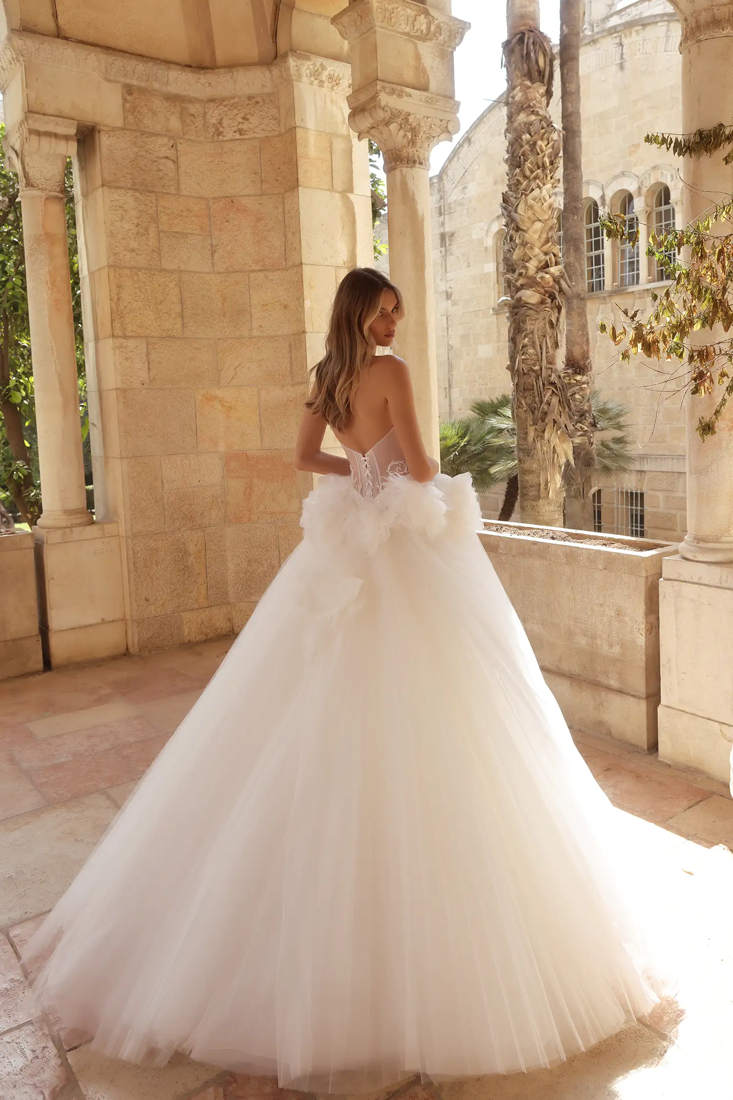 Strapless ballgown in satin and sunray pleated tulle, with cat-eye sweetheart neckline, water crystal appliqués and water crystal drops, and dimensional organza flowers at hips.