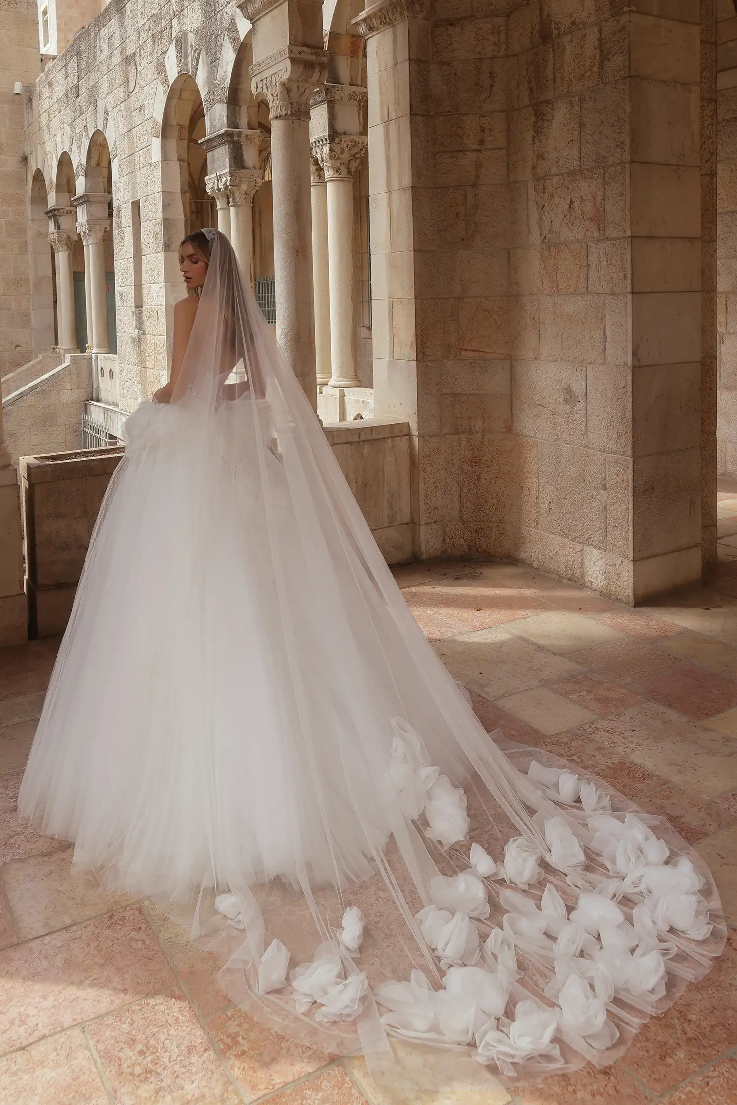 Strapless ballgown in satin and sunray pleated tulle, with cat-eye sweetheart neckline, water crystal appliqués and water crystal drops, and dimensional organza flowers at hips.