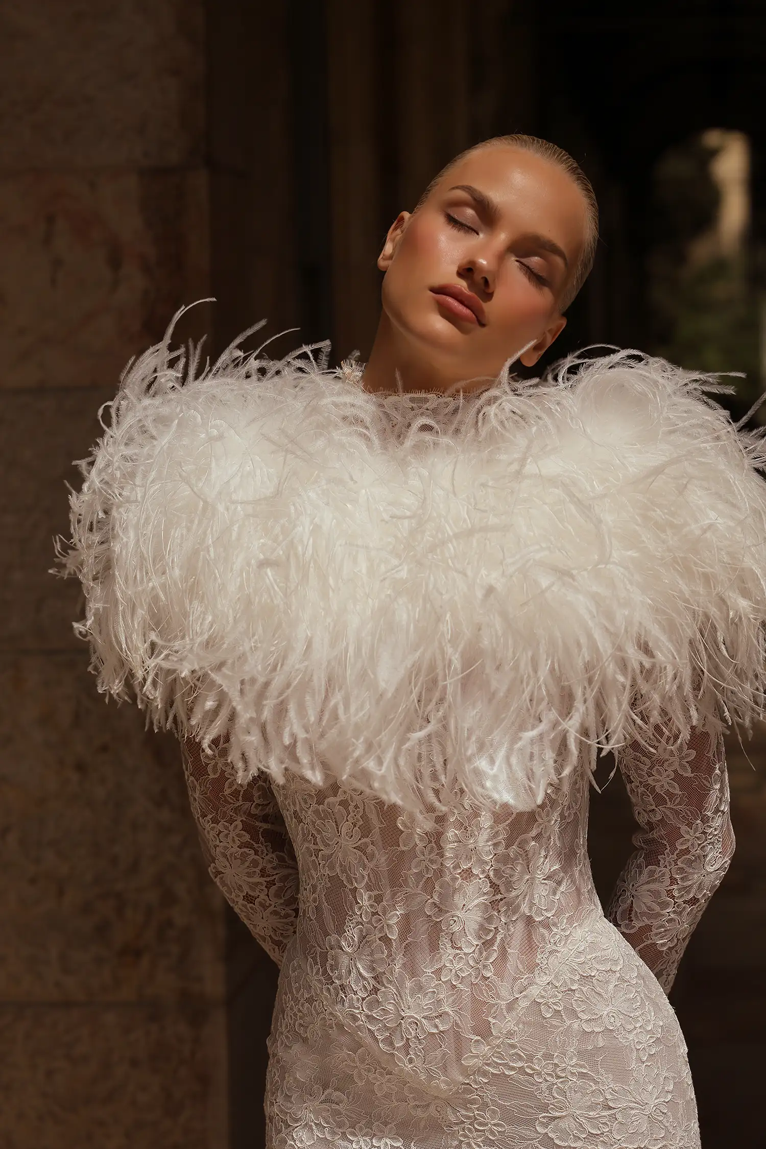 High-neck alençon lace mermaid gown with basque waist, tiered skirt, long puff sleeves, and pearl buttons.