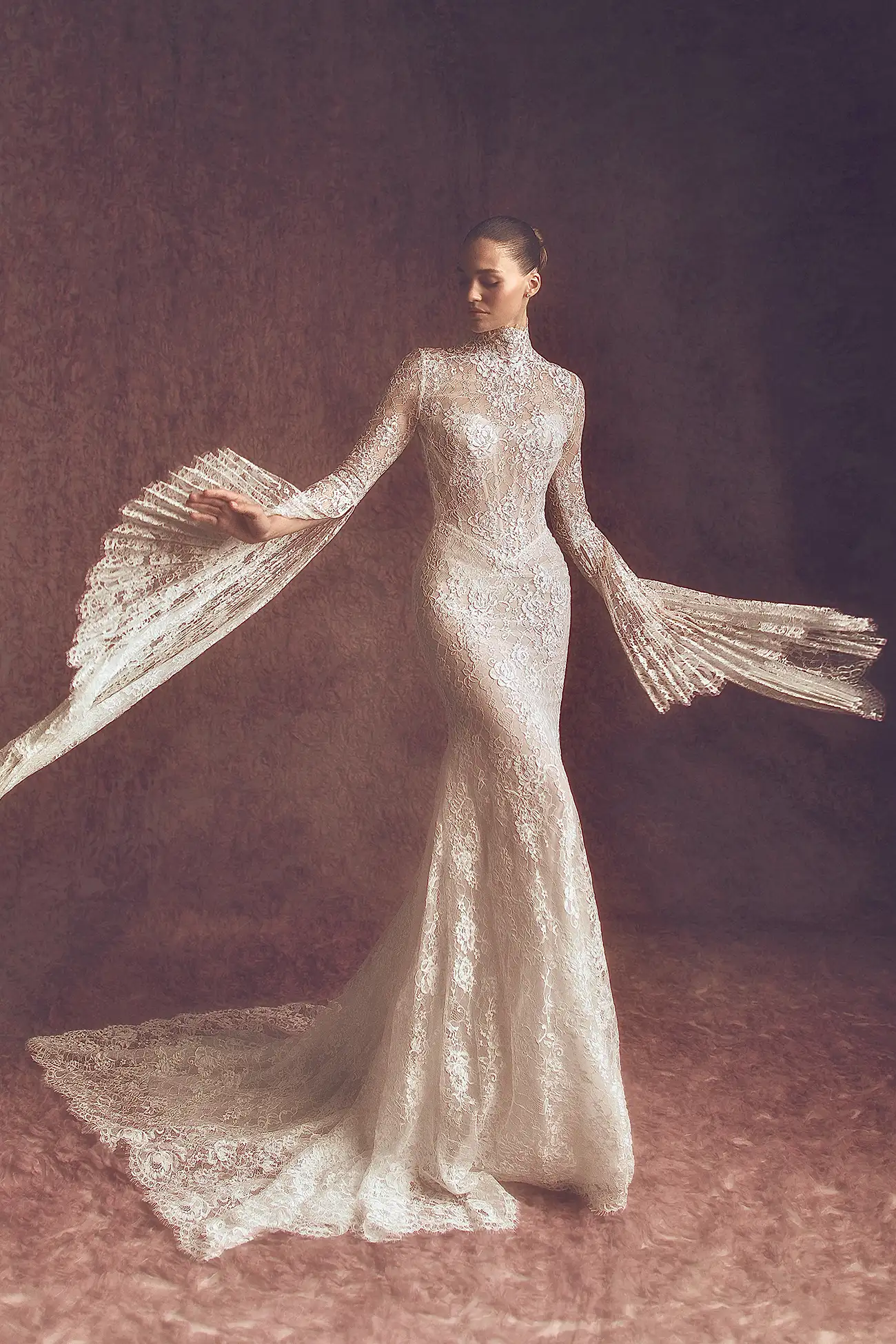 Alençon lace high neck long sleeve sheath with open back and pleated bell sleeves.