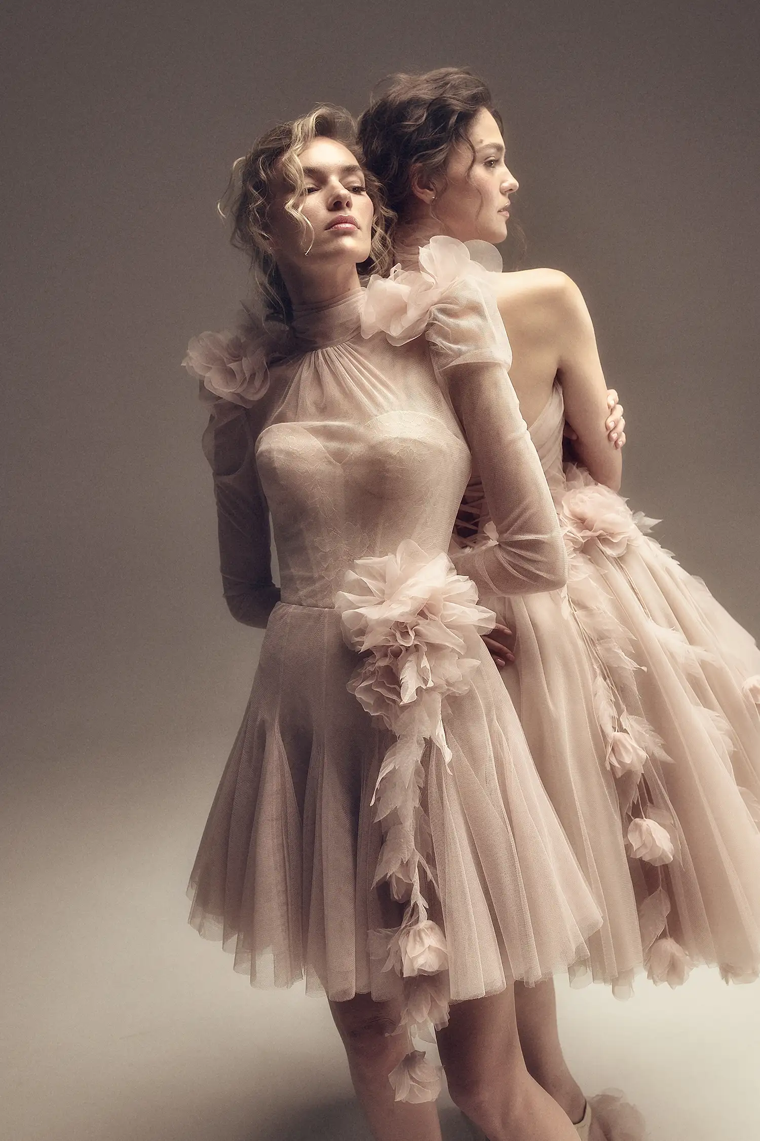 Blush pink high neck soft tulle minidress with chantilly lace sweetheart bodice, gathered tulle long sleeves, and dimensional organza flower and hanging vine details.